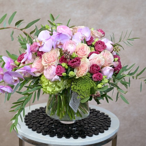 Lavender orchids blush roses and green hydrangea in a glass vase arranged by Cary luxury florist